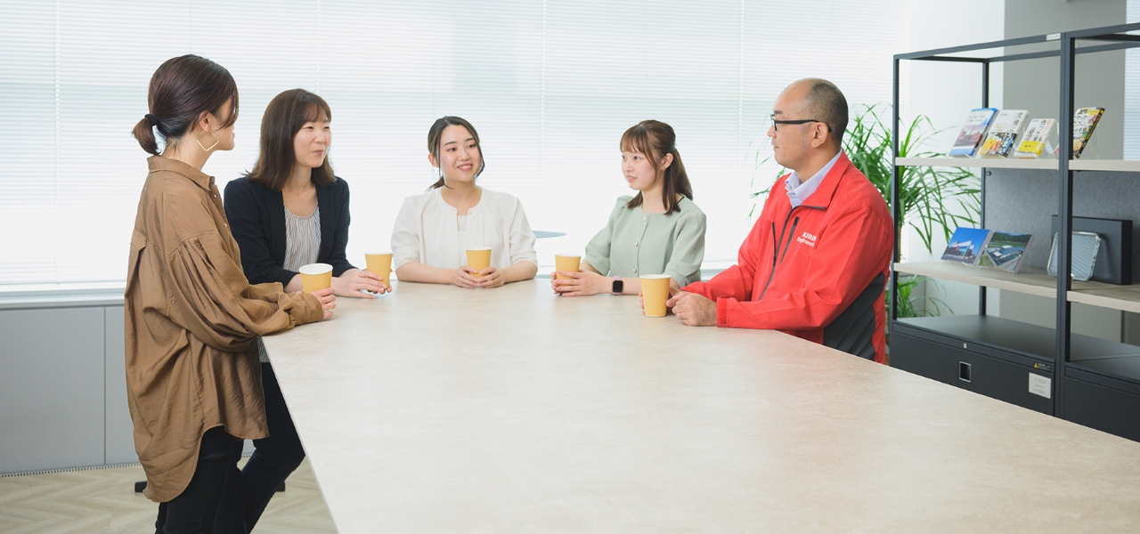 オフィスでコーヒーを飲みながら会話している社員たち