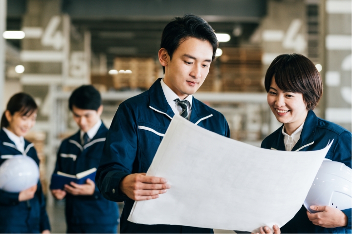 設計図を確認する作業服姿の男女スタッフ