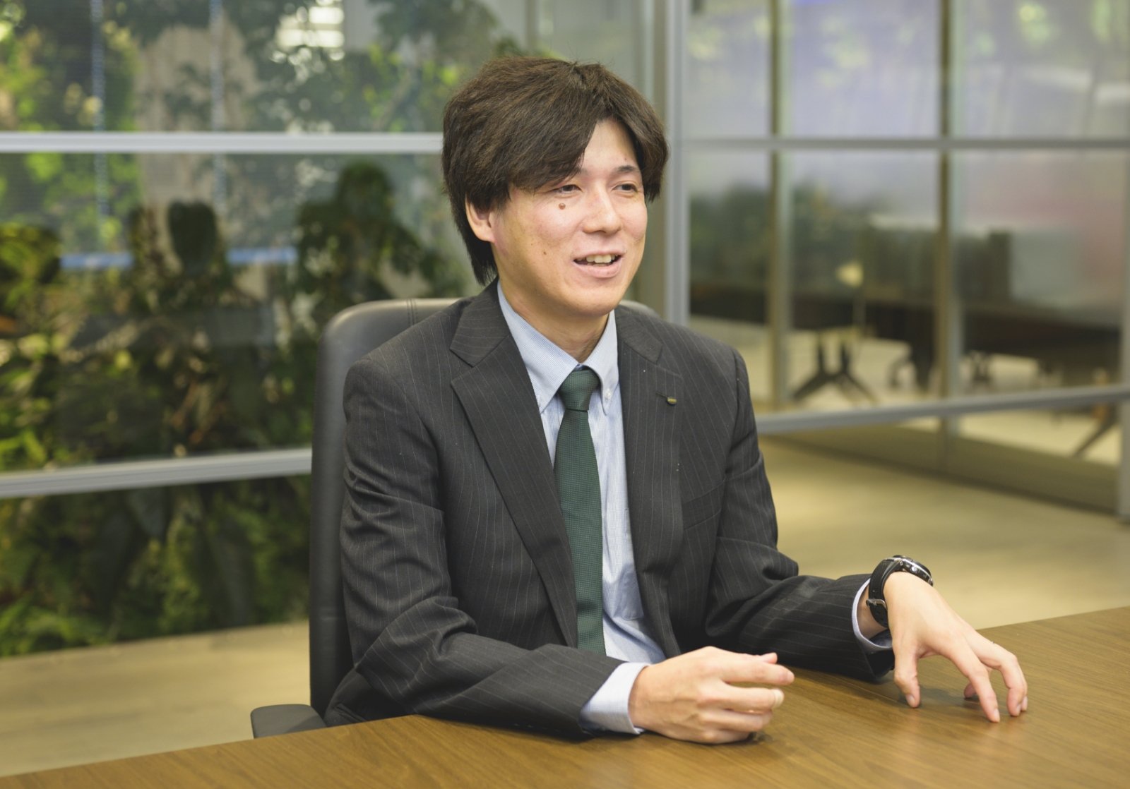 スーツ姿の甲斐 正和がオフィスでインタビューを受けている様子