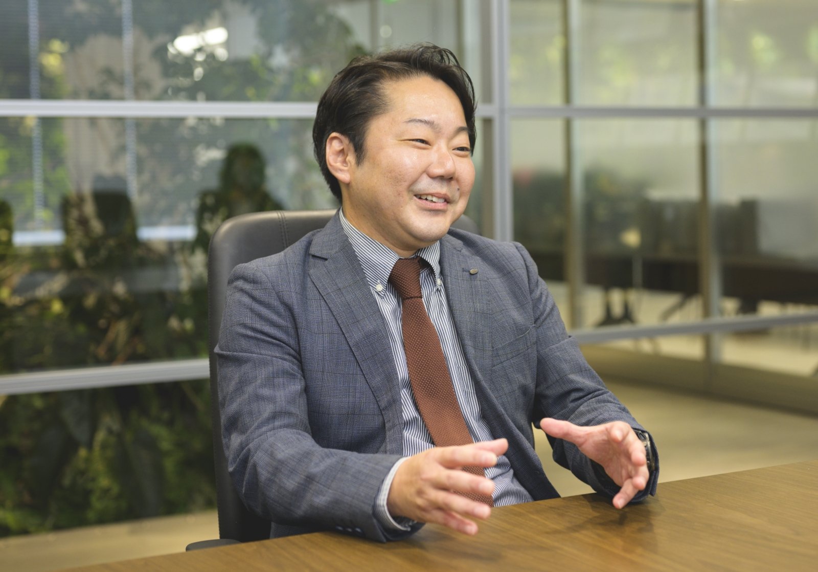 スーツ姿の内田 宗正がオフィスでインタビューを受けている様子