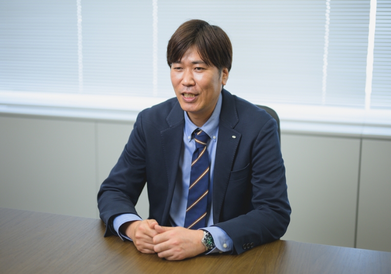 スーツ姿の伊藤 崇がオフィスでインタビューに答えている様子