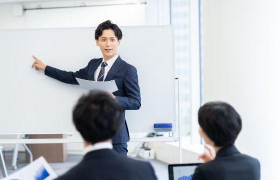研修でホワイトボードを使って説明するビジネスマン