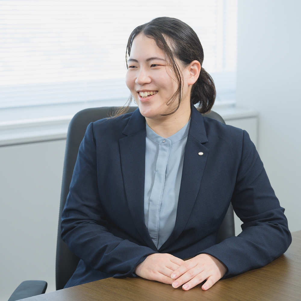 スーツを着た女性社員が会議室で笑顔を見せている様子
