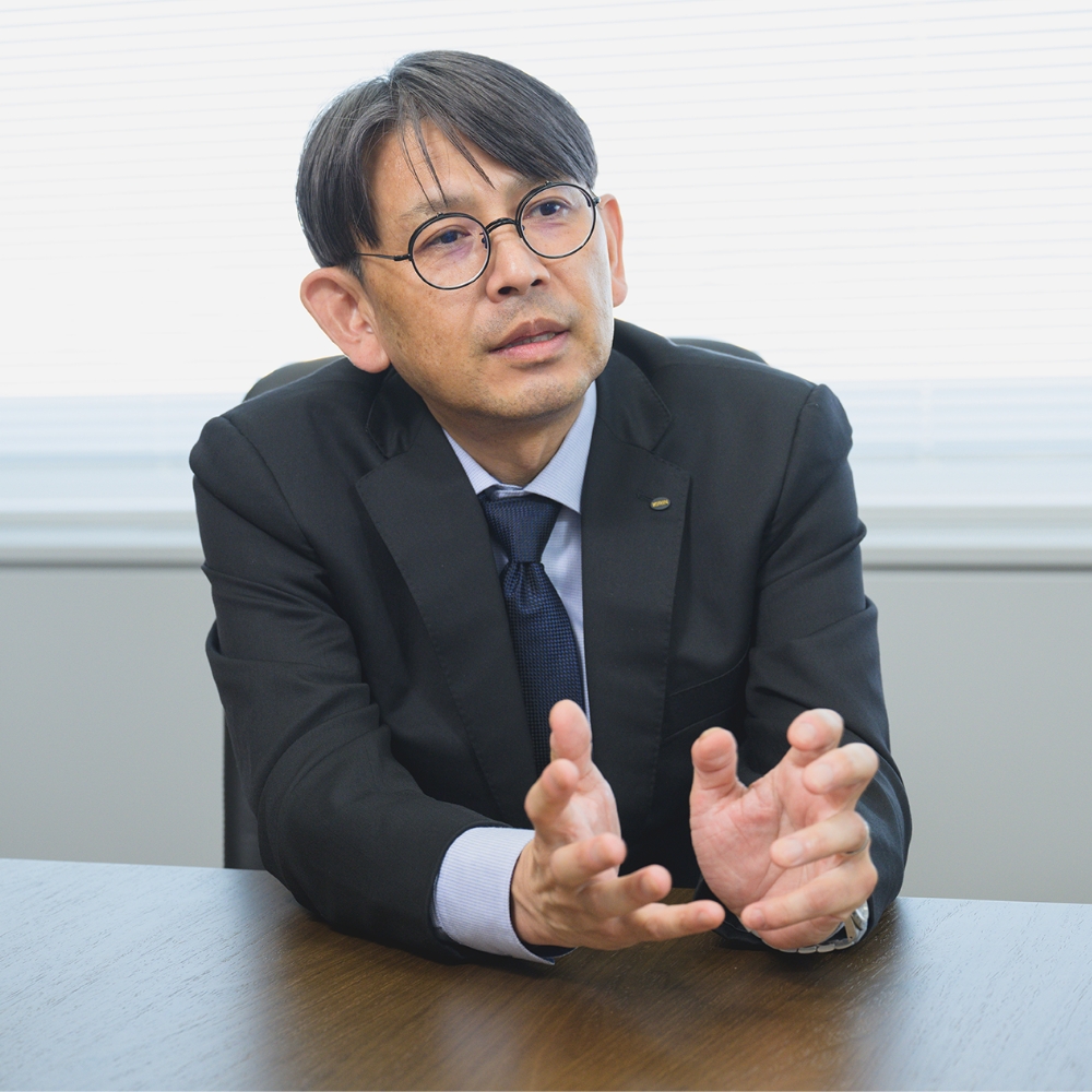 スーツを着た男性社員が会議室で説明している様子