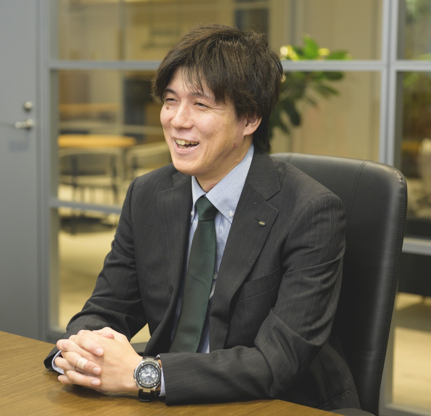 スーツ姿の甲斐正和がオフィスでインタビューを受けている様子