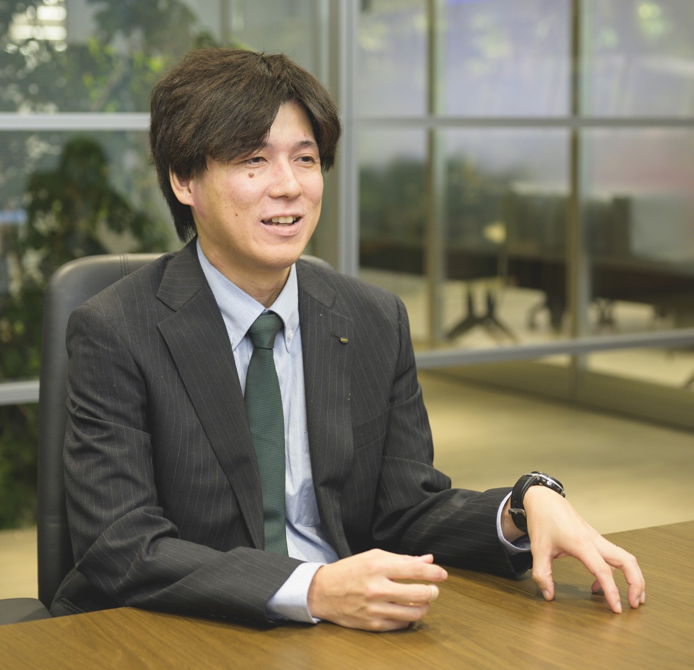 スーツ姿の甲斐正和がオフィスでインタビューを受けている様子