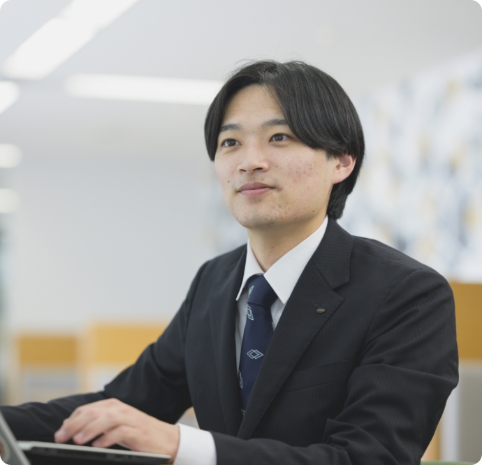 櫻井敬太がオフィスでスーツを着てパソコンを操作している