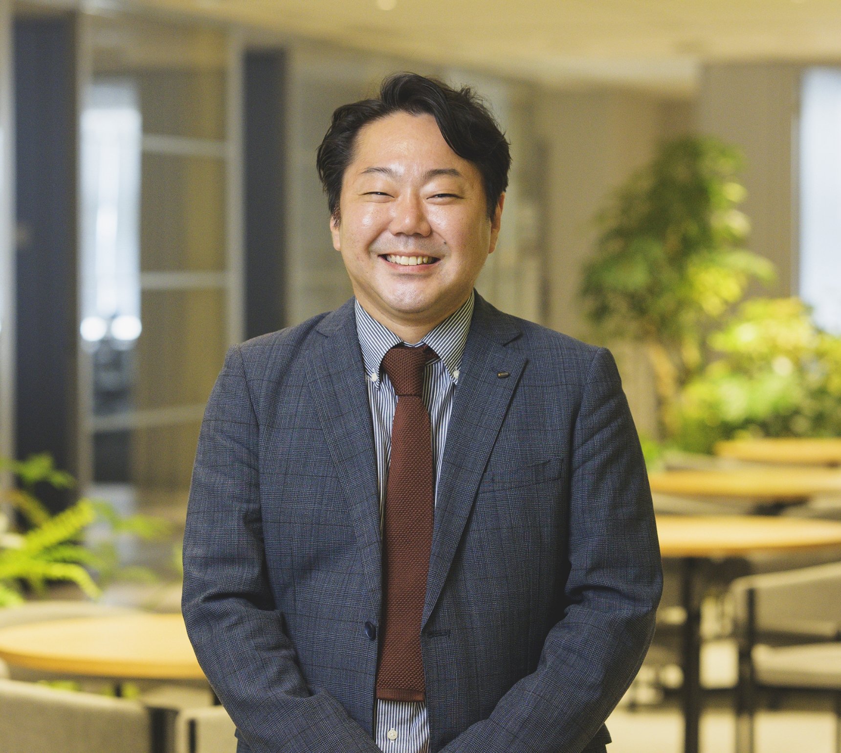 オフィスでスーツを着て満面の笑みを見せる内田宗正